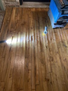 wide angle shot showing several square feet of buckling hardwood floor and dehumidifier deployed to repair water damage in Chicago's fulton market